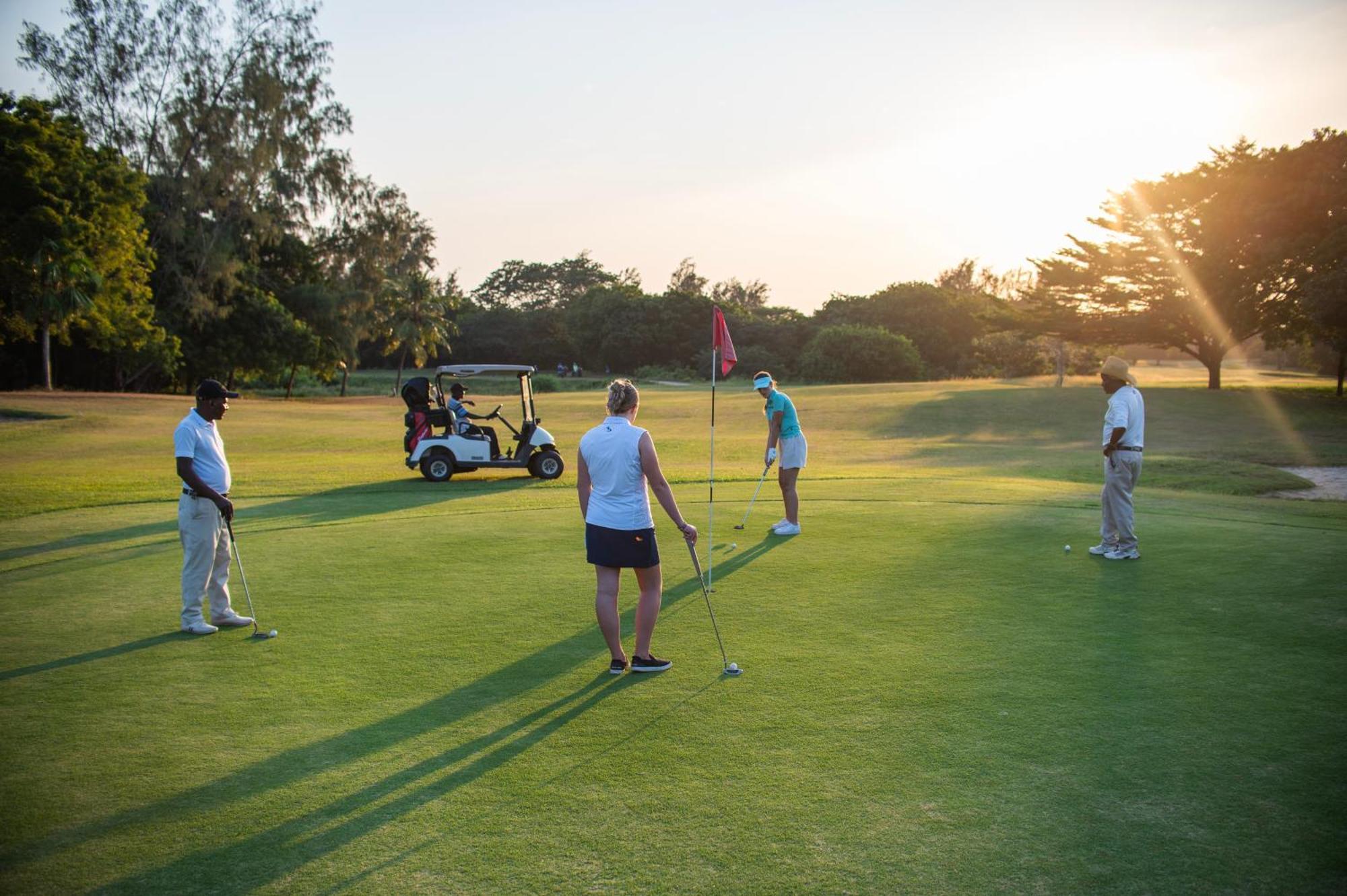 레저 로지 비치 앤 골프 리조트 디아니 해변 외부 사진 Golfers putting on the 18th green at the Royal Pines Resort